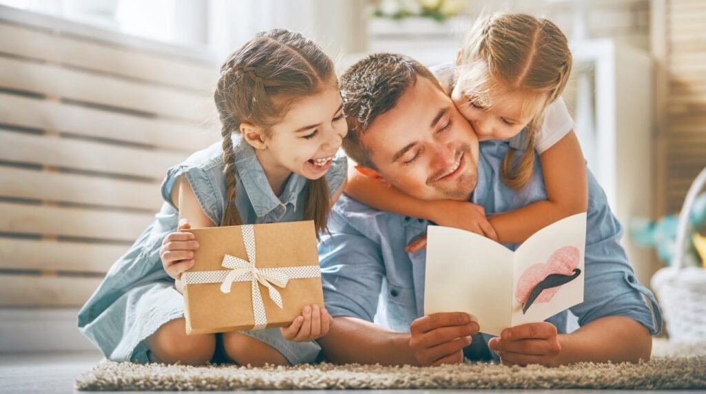 hombre leyendo una targeta a sus dos hijas